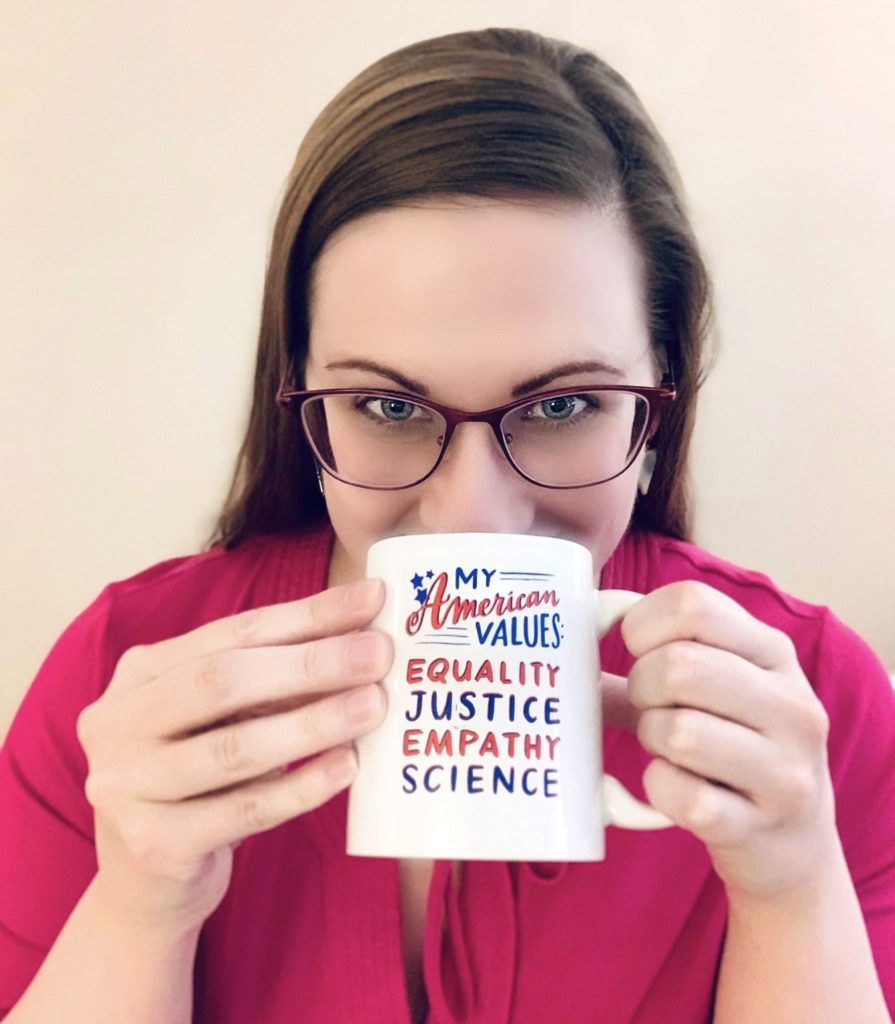 Jessica drinking out of a mug that says My American Values: Equality, Justice, Empathy, Science